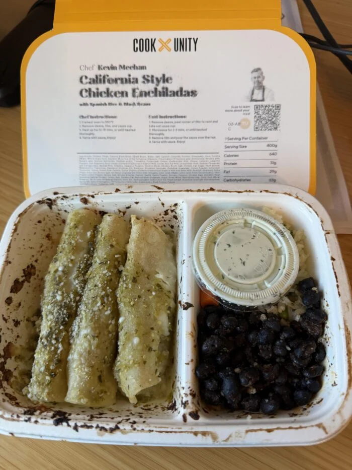 CookUnity chicken enchiladas with green sauce next to black beans and a sauce cup in the tray, chef label behind
