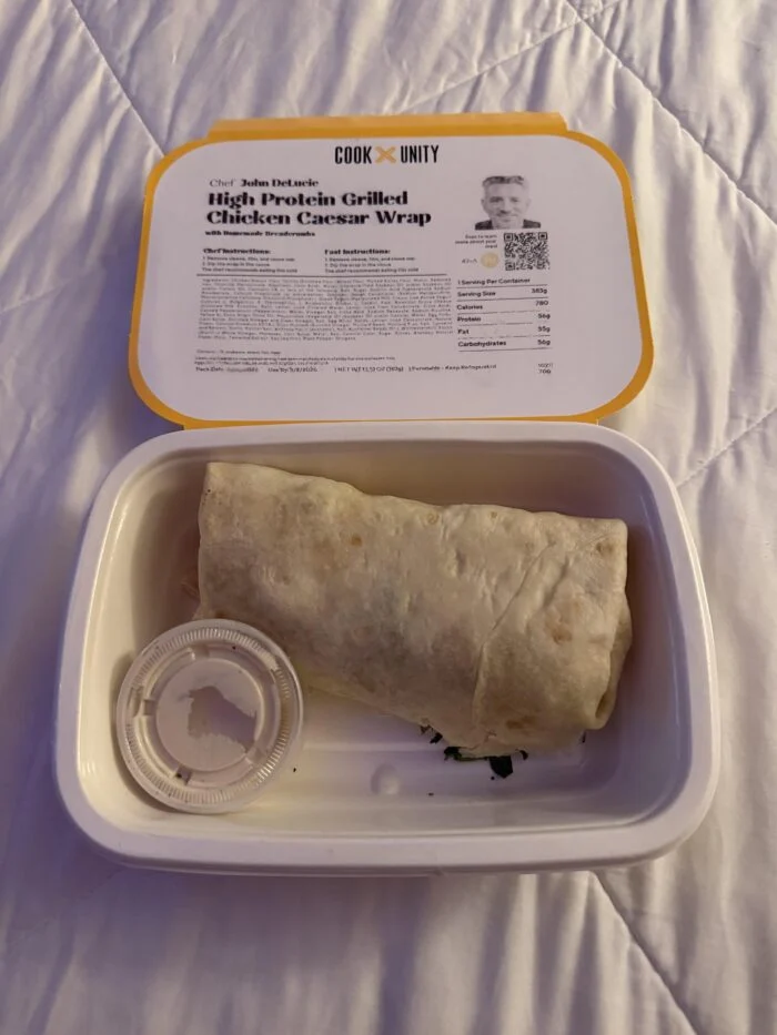 CookUnity high-protein grilled chicken Caesar wrap with a dressing cup in its tray.