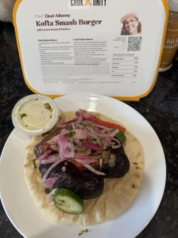 CookUnity kofta smash burger with pickled onions on a flatbread on a white plate, chef label behind