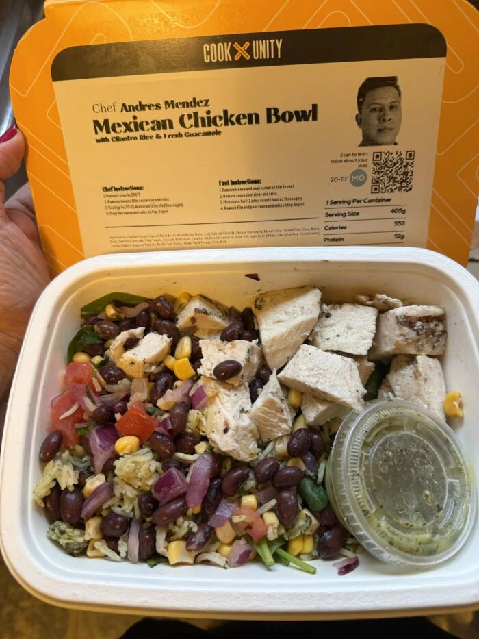 CookUnity Mexican chicken bowl with beans, corn and rice and a guacamole cup in the tray, chef label held up behind