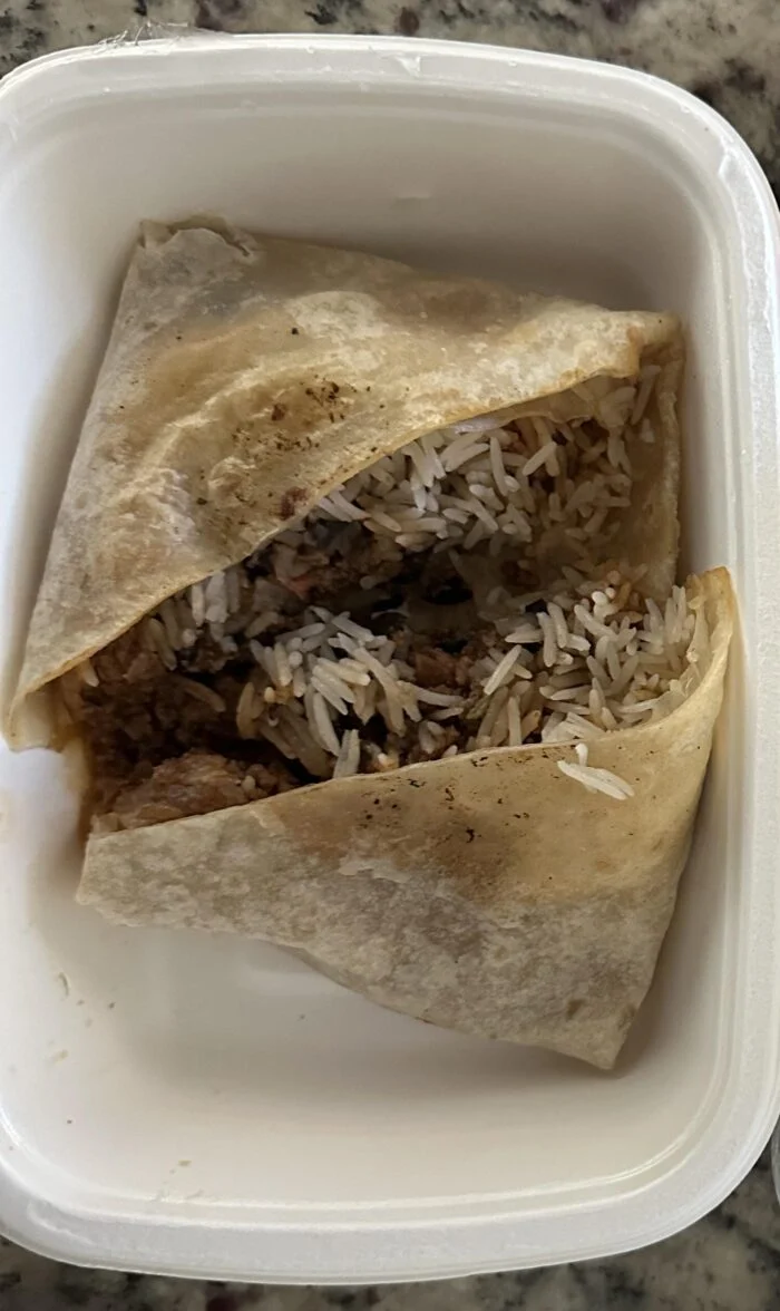 Reader photo of a CookUnity Mission Style beef and rice burrito cut in half in its delivery tray