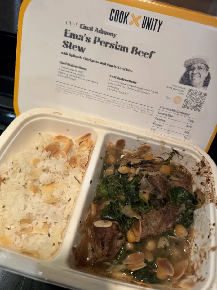 CookUnity Persian beef stew with spinach and chickpeas next to almond rice in the tray, chef label behind
