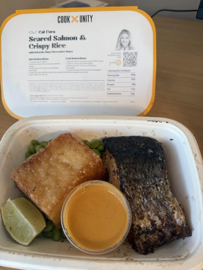 CookUnity seared salmon with a crispy rice cake, lime and a sauce cup in the tray, chef label behind
