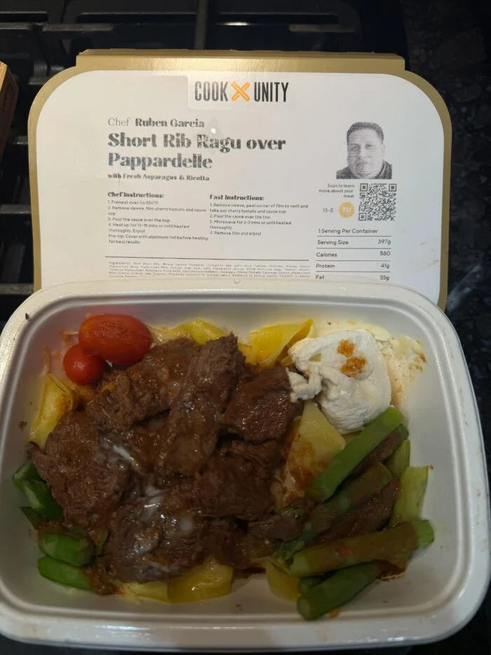 CookUnity short rib ragu over pappardelle with asparagus, ricotta and cherry tomatoes in the tray, chef label behind
