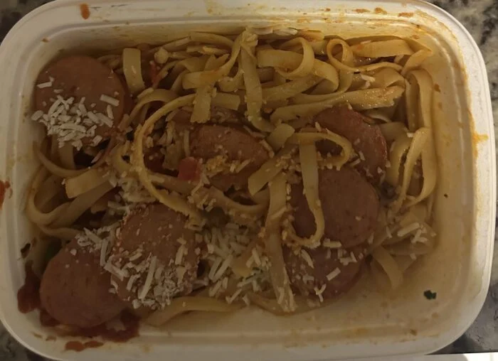 CookUnity fettuccine in red sauce with sliced sausage and shredded Parmesan