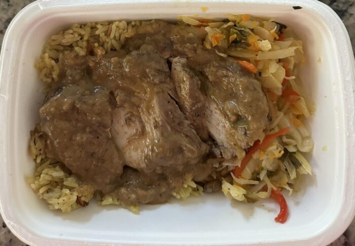 Reader photo of CookUnity sliced spicy jerk chicken in gravy over yellow rice with steamed cabbage and peppers in its delivery tray