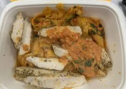 Reader photo of CookUnity Tuscan baked chicken pappardelle with sliced chicken and sun dried tomato sauce in its delivery tray
