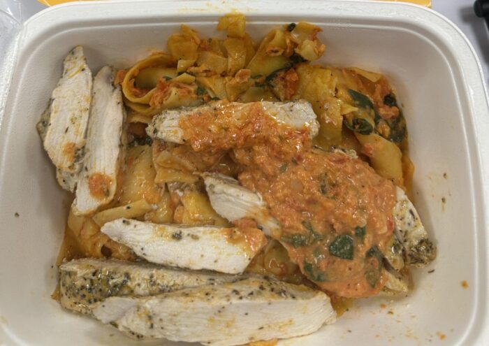 Reader photo of CookUnity Tuscan baked chicken pappardelle with sliced chicken and sun dried tomato sauce in its delivery tray