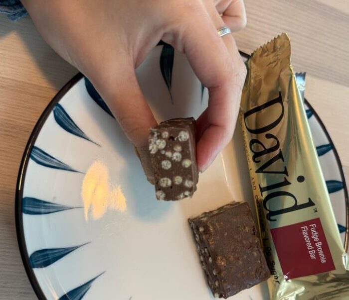 David Fudge Brownie protein bar cut open beside its wrapper.