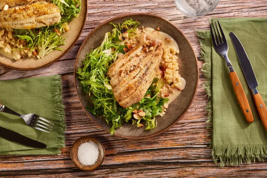 Tilapia over couscous with citrus beurre blanc and frisée arugula salad